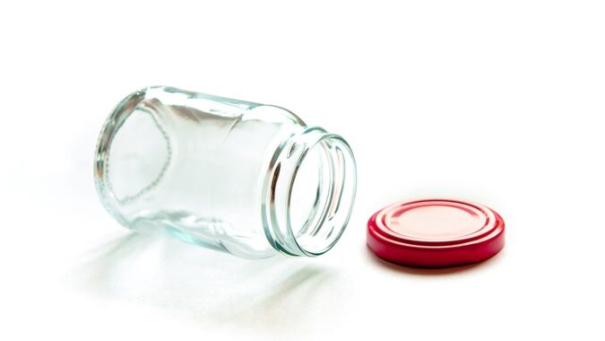 empty glass jar on its side with lid off.