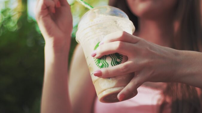 woman with Starbucks iced coffee in plastic cup and straw.