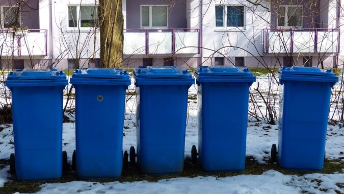 five blue wheelie bins in the snow.