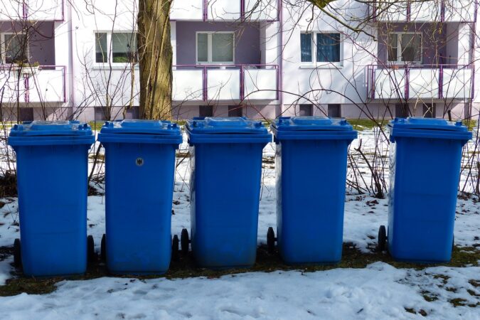 five blue wheelie bins in the snow.