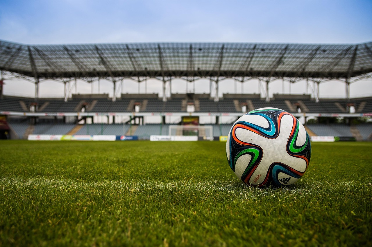 football on the pitch in the foreground of a stadium.