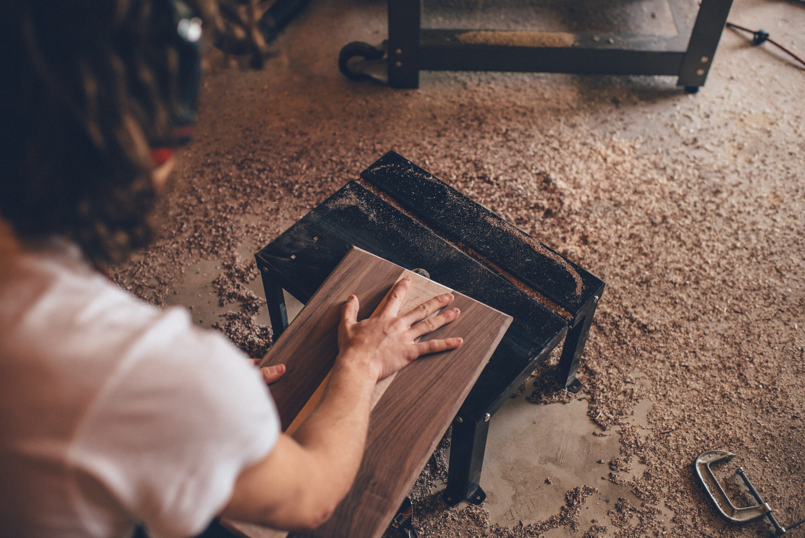 man sawing piece of wood and creating sawdust.