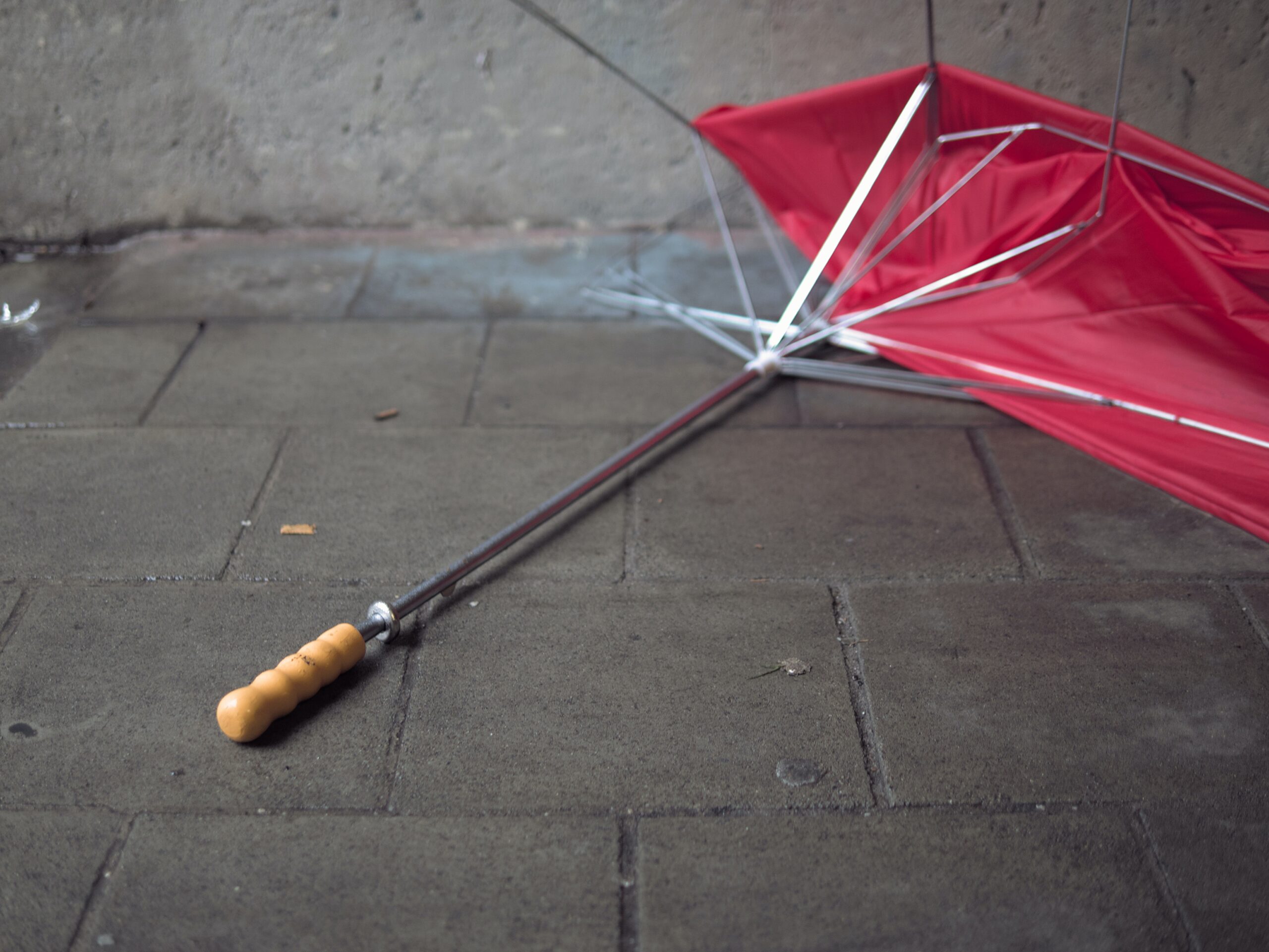broken umbrella lying on the pavement.
