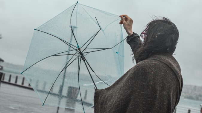 woman struggling with a broken umbrella in the rain.