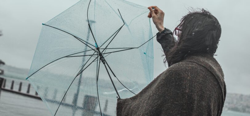 woman struggling with a broken umbrella in the rain.