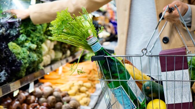 person shopping in a supermarket with basket in hand.